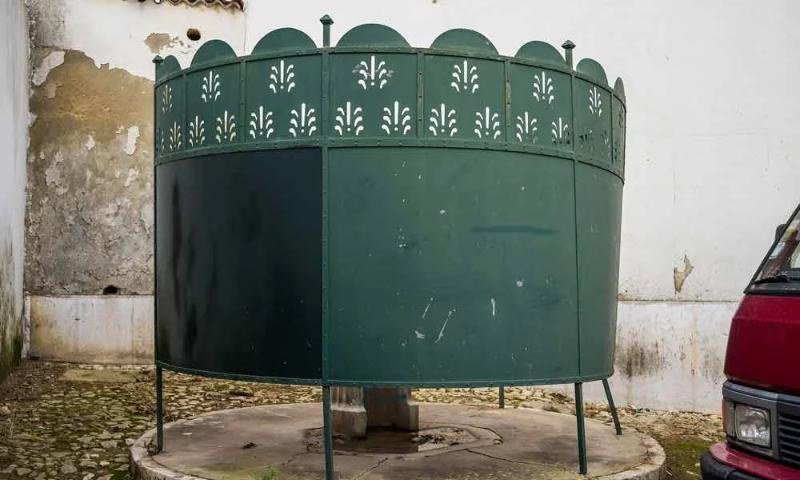 Um chafariz verde num pátio de pedra